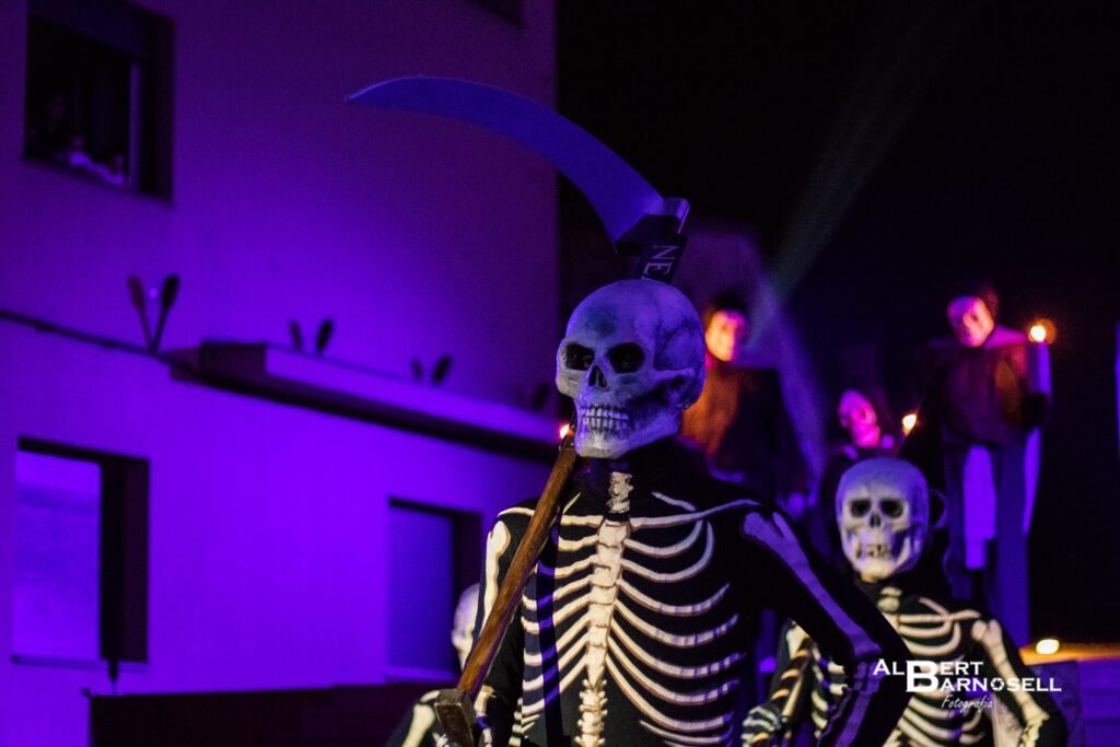 Primer pla del Capdanser amb la dalla sota la il·luminació lila teatral de la Plaça de Verges.