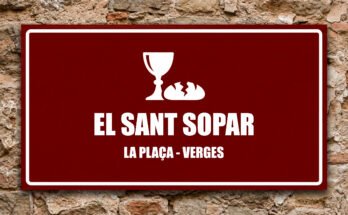 Icona d'un calze i pa partit sobre fons grana, símbol de l'Eucaristia al Sant Sopar de Verges.