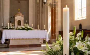 Ciri pasqual i flors blanques en una església lluminosa