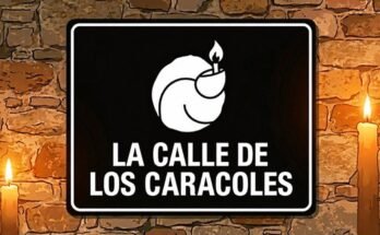 Cartel negro de la Calle de los Caracoles con un caracol y una llama blancos, entre dos velas.
