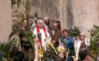 Bendición de Ramos en Verges con el sacerdote y vecinos que alzan palmas y ramas.
