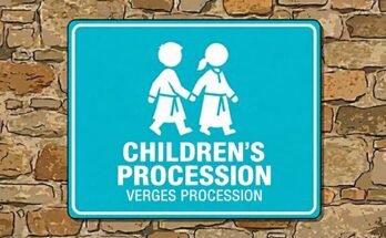 Two white children holding hands on a blue sign reading “Children's Procession · Verges Procession”.
