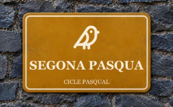 Rètol ocre sobre un mur de pissarra amb un pictograma i el text «SEGONA PASQUA».