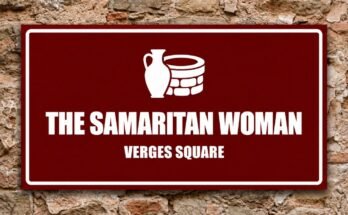 White water jug beside a well on a red sign reading “The Samaritan Woman · Verges Square”.