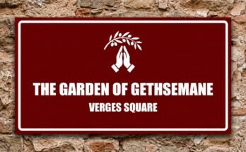 White praying hands beneath an olive branch on a red sign reading “The Garden of Gethsemane · Verges Square”.
