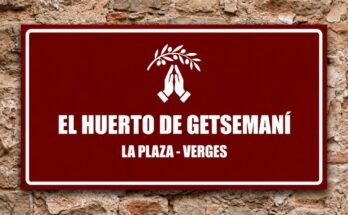 Manos blancas en oración bajo una rama de olivo en un cartel granate «El Huerto de Getsemaní · La Plaza, Verges».