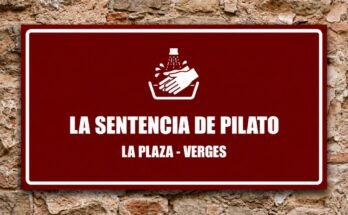 Manos blancas lavándose bajo un chorro de agua en un cartel granate «La Sentencia de Pilato · La Plaza, Verges».