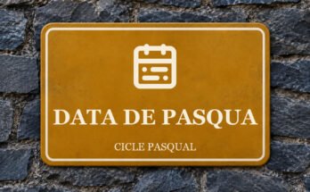 Rètol ocre sobre un mur de pissarra amb un pictograma i el text «DATA DE PASQUA».