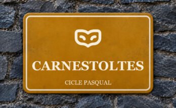 Rètol ocre sobre un mur de pissarra amb un pictograma i el text «CARNESTOLTES».