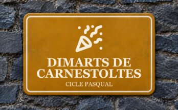 Rètol ocre sobre un mur de pissarra amb un pictograma i el text «DIMARTS DE CARNESTOLTES».