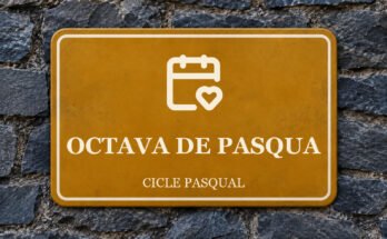 Rètol ocre sobre un mur de pissarra amb un pictograma i el text «OCTAVA DE PASQUA».
