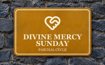 Ochre sign on a slate wall with a pictogram and the words “DIVINE MERCY SUNDAY”.