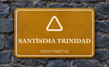 Rótulo ocre sobre un muro de pizarra con un pictograma y el texto «SANTÍSIMA TRINIDAD».