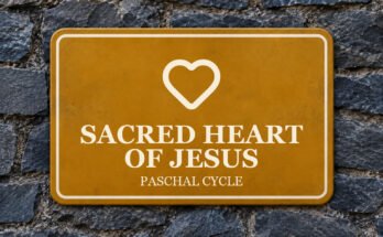 Ochre sign on a slate wall with a pictogram and the words “SACRED HEART OF JESUS”.