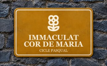 Rètol ocre sobre un mur de pissarra amb un pictograma i el text «IMMACULAT COR DE MARIA».