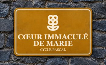 Panneau ocre sur un mur d’ardoise, avec un pictogramme et le texte «CŒUR IMMACULÉ DE MARIE».