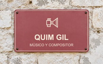 Rótulo rosa sobre un muro de piedra caliza con el texto «QUIM GIL» y un pictograma.
