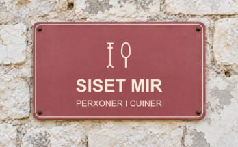 Rètol rosa sobre un mur de pedra calcària amb el text «SISET MIR» i un pictograma.