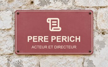 Panneau rose sur un mur en pierre calcaire portant le texte «PERE PERICH» et un pictogramme.