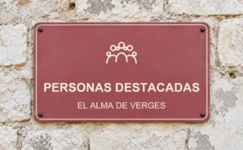 Rótulo rosa sobre un muro de piedra caliza con el texto «PERSONAS DESTACADAS» y un pictograma.