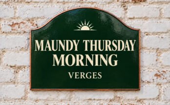 Arched green sign reading “MAUNDY THURSDAY MORNING”, with a rising sun, on a whitewashed brick wall.