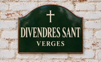 Rètol verd arquejat amb «DIVENDRES SANT» i una creu, sobre un mur de maó emblanquinat.