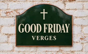 Arched green sign reading “GOOD FRIDAY”, with a cross, on a whitewashed brick wall.
