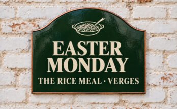 Arched green sign reading “EASTER MONDAY”, with a bowl of rice and a spoon, on a whitewashed brick wall.